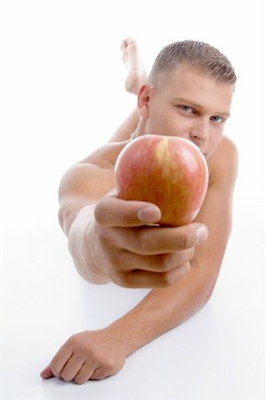 physical fit food - laying fit guy showing apple on an isolated background Stock Photo - Budget Royalty-Free & Subscription, Code: 400-04546912