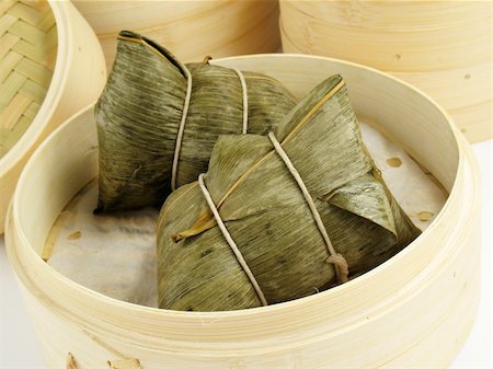 Steamed Chinese rice dumplings (zongzi) wrapped in bamboo leaves, filled with glutinous/sticky rice, pork, mushrooms, and peanuts. These are eaten during the Dragon Boat Festival. Stock Photo - Budget Royalty-Free & Subscription, Code: 400-04547879