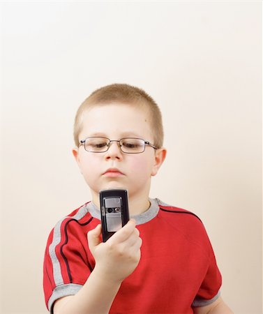 sibling sad - the small boy in glasses uses mobile phone Stock Photo - Budget Royalty-Free & Subscription, Code: 400-04549162