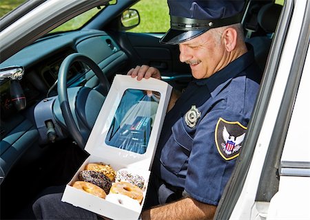 simsearch:693-03782773,k - Policeman in his squad car, hungrily looking at a box of donuts. Stockbilder - Microstock & Abonnement, Bildnummer: 400-04540333
