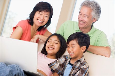 simsearch:400-04044137,k - Couple with two young children in living room with laptop smilin Stock Photo - Budget Royalty-Free & Subscription, Code: 400-04540521