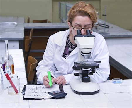 scientist and teacher photo - Female researcher taking notices while she is using a microscope.All inscriptions are mine. Stock Photo - Budget Royalty-Free & Subscription, Code: 400-04540643