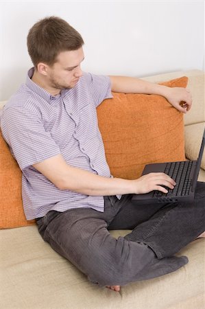 simsearch:400-04999709,k - casual guy sitting on sofa with laptop Photographie de stock - Aubaine LD & Abonnement, Code: 400-04540881