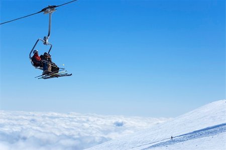 skiers and chairs lifts in snow - Chair lift with skiers at ski resort above the clouds. Snowboarder on the slope. Stock Photo - Budget Royalty-Free & Subscription, Code: 400-04542395