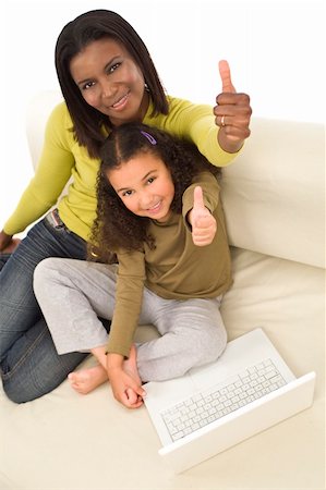 A beautiful young African American mother and her mixed race young daughter using a laptop at home and giving a thumbs up Foto de stock - Royalty-Free Super Valor e Assinatura, Número: 400-04543439