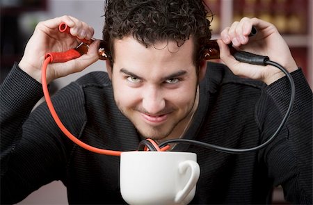 simsearch:400-04554624,k - Young man holding jumper cables coming out of coffee mug Stock Photo - Budget Royalty-Free & Subscription, Code: 400-04554626