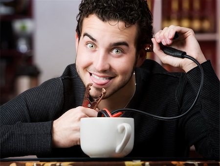 electricity humor - Young man holding jumper cables coming out of coffee mug Stock Photo - Budget Royalty-Free & Subscription, Code: 400-04554627