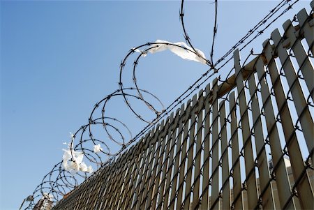 simsearch:600-02886164,k - Fence with barbed wire against blue sky Photographie de stock - Aubaine LD & Abonnement, Code: 400-04559271
