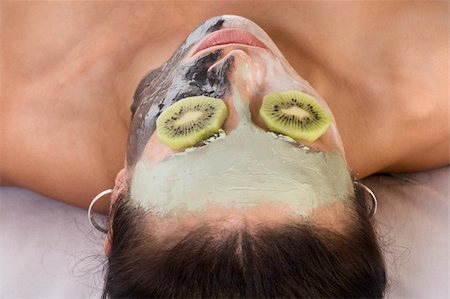 simsearch:400-03935575,k - Woman lying down on her back in spa, with special facial mask applied on her face. The mask consist of three colors, each cover different part and eyes are covered by slice of kiwi Stock Photo - Budget Royalty-Free & Subscription, Code: 400-04550094