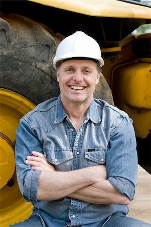 Handsome forties construction worker is sitting against his digger smiling with his arms folded. Foto de stock - Super Valor sin royalties y Suscripción, Código: 400-04550233