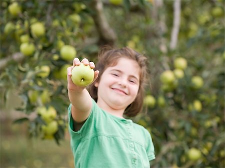 Girl Smiling Holding up an Apple Stock Photo - Budget Royalty-Free & Subscription, Code: 400-04551317