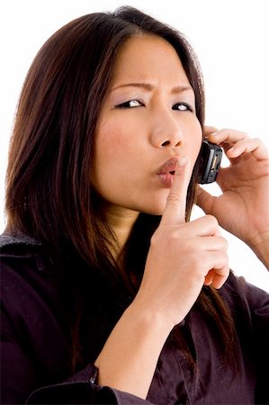 young corporate woman talking on cell phone and shushing on an isolated background Stock Photo - Budget Royalty-Free & Subscription, Code: 400-04551702