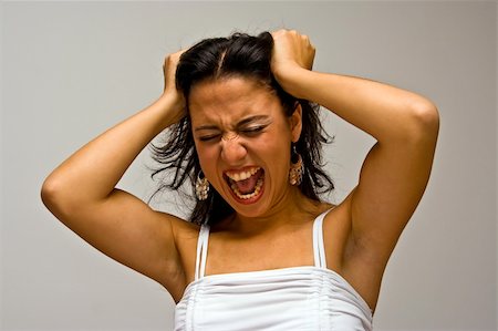 person screaming pulling hair - A young beautiful latina woman screeming of frustration and pulling her hair with both hands wearing a white shirt, isolated on white Stock Photo - Budget Royalty-Free & Subscription, Code: 400-04567182