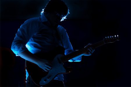 Close up on a guitarist playing at a dramatically blue light show. Stockbilder - Microstock & Abonnement, Bildnummer: 400-04567825