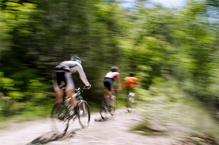 simsearch:628-02228134,k - Blurred panning shot of three mountain bikers riding through the forest. Stockbilder - Microstock & Abonnement, Bildnummer: 400-04568440