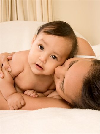 simsearch:400-04530129,k - Mom and son lying down on bed and mother embracing the infant baby, who looks at camera with serious facial expression Stock Photo - Budget Royalty-Free & Subscription, Code: 400-04568744