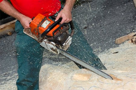 simsearch:400-04364349,k - Close up of a woodcarver creating a sculpture from a pine log, using a chainsaw. Sawdust flying. Stock Photo - Budget Royalty-Free & Subscription, Code: 400-04560812