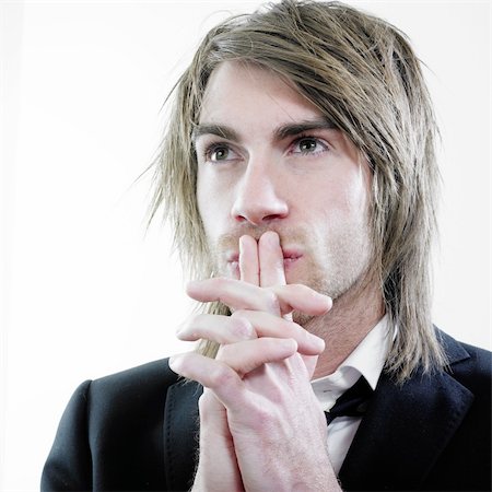 Studio portrait of an attractive caucasian man with concentrating and thinking facial expression holding his folded hands in front of his mouth and watching Foto de stock - Super Valor sin royalties y Suscripción, Código: 400-04562684