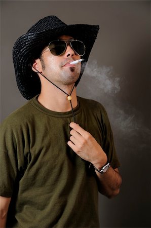 Portrait of young trendy man smoking with cowboy hat Stock Photo - Budget Royalty-Free & Subscription, Code: 400-04574561