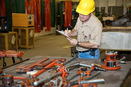 Auditor taking inventory of tools in an industrial factory.  Welding equipment is visible in the background. Stock Photo - Budget Royalty-Free & Subscription, Code: 400-04574820