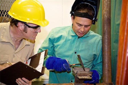 Welder hammering metal as an auditor looks on inspecting his work.  Focus on the welder.   All work is accurately depicted in accordance with industry  code and safety standards. Stock Photo - Budget Royalty-Free & Subscription, Code: 400-04574821