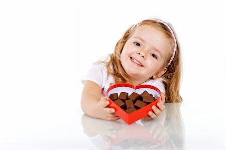 simsearch:400-05701644,k - Happy little girl with chocolate in heart shaped box - isolated with reflection Stock Photo - Budget Royalty-Free & Subscription, Code: 400-04575322