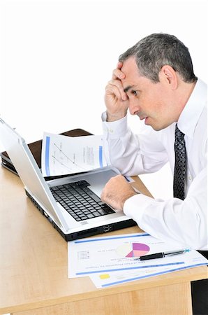 desk trader - Stressed businessman sitting at his desk isolated on white background Stock Photo - Budget Royalty-Free & Subscription, Code: 400-04576378