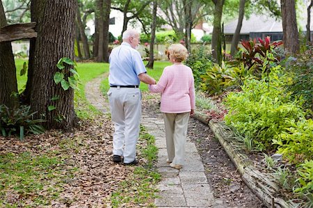 simsearch:400-04109826,k - Senior husband and wife holding hands and walking down a garden path. Fotografie stock - Microstock e Abbonamento, Codice: 400-04571321