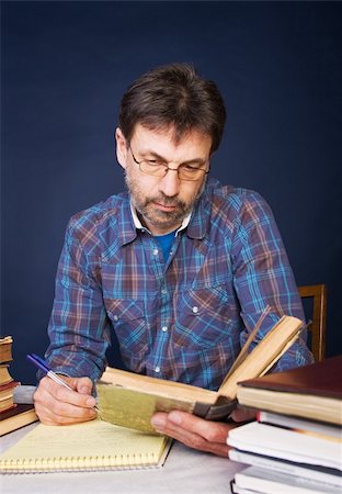 scientist and teacher photo - Researcher taking notes; he is surrounded by heaps of books. Stock Photo - Budget Royalty-Free & Subscription, Code: 400-04572669