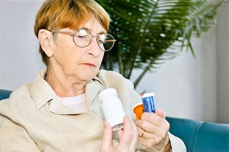 senior at home with medication - Elderly woman reading warning labels on pill bottles with medication Stock Photo - Budget Royalty-Free & Subscription, Code: 400-04587607