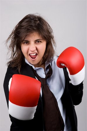 businesswoman wearing boxing gloves with confident attitude. grey background. Photographie de stock - Aubaine LD & Abonnement, Code: 400-04588634