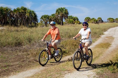 seniors bike riding on beach - Senior couple bicycling at the beach, wearing safety helmets and sunglasses. Stock Photo - Budget Royalty-Free & Subscription, Code: 400-04588826