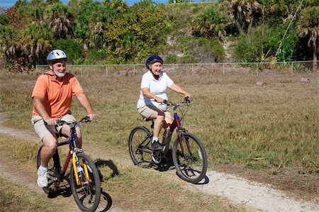 Happy senior couple riding their bikes through the park. Foto de stock - Super Valor sin royalties y Suscripción, Código: 400-04588828