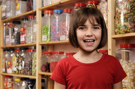 spoiled for choice - young girl smiling at camera in sweet shop Stock Photo - Budget Royalty-Free & Subscription, Code: 400-04589354