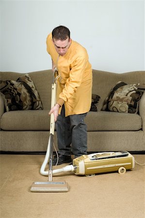 simsearch:670-03484359,k - A young man vacuuming the carpet with an old vacuum cleaner Stock Photo - Budget Royalty-Free & Subscription, Code: 400-04594821