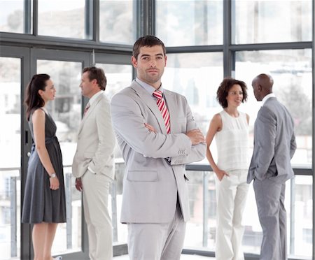 simsearch:400-04113098,k - Attractive standing businessman looking at the camera with his team in the background Stock Photo - Budget Royalty-Free & Subscription, Code: 400-04598691