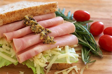 simsearch:400-07407920,k - Tasty open sandwich with green lettuce, grated cheese, smoked ham and wholegrain mustard on wholewheat bread with rosemary and tomatoes on chopping board Photographie de stock - Aubaine LD & Abonnement, Code: 400-04598772