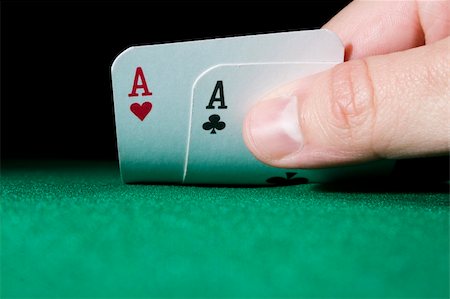 simsearch:400-04401278,k - Hand holding a pair of aces on green gaming table - focus on cards and hand Photographie de stock - Aubaine LD & Abonnement, Code: 400-04599109