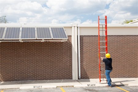 simsearch:400-05380326,k - Wide angle view of a construction worker preparing to climb on to the roof of a building to work on solar panels. Stock Photo - Budget Royalty-Free & Subscription, Code: 400-04590676