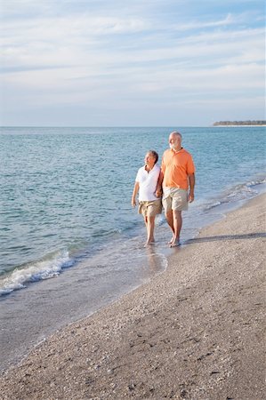 simsearch:400-04109826,k - Financially secure retired senior couple enjoys a walk on a beautiful beach.  Wide angle view with room for text. Fotografie stock - Microstock e Abbonamento, Codice: 400-04606980