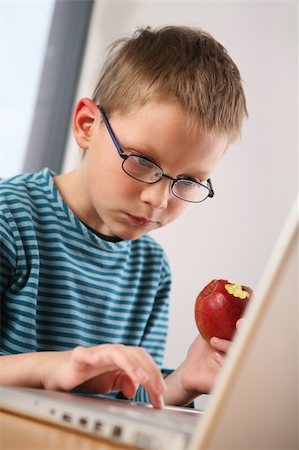 family eating computer - Young boy using a laptop while eating an apple. Stock Photo - Budget Royalty-Free & Subscription, Code: 400-04607178