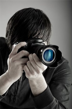 simsearch:400-04270950,k - Young man holding a professional DSLR camera and taking pictures Stockbilder - Microstock & Abonnement, Bildnummer: 400-04607642