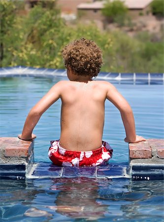 Young boy sitting on the edge of a swimming pool Stock Photo - Budget Royalty-Free & Subscription, Code: 400-04601527