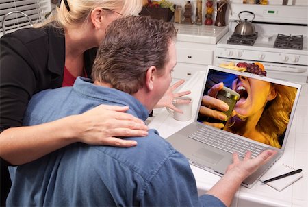 Couple In Kitchen Using Laptop with Singing Woman on the Screen. Stock Photo - Budget Royalty-Free & Subscription, Code: 400-04602505