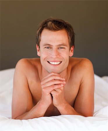 Isolated young man relaxing in bed smiling at the camera Stock Photo - Budget Royalty-Free & Subscription, Code: 400-04614608