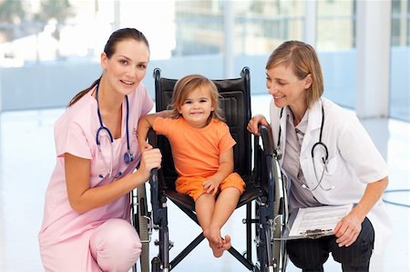 Little girl in a wheelchair with attractive nurse and doctor Stock Photo - Budget Royalty-Free & Subscription, Code: 400-04614648