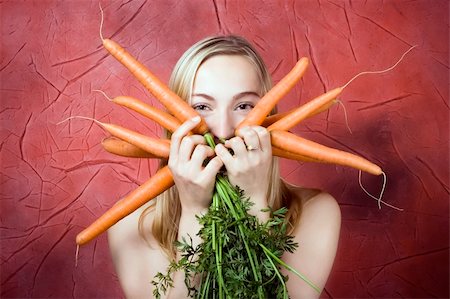 Smiling young woman with fresh carrots. Red background. Stock Photo - Budget Royalty-Free & Subscription, Code: 400-04616145