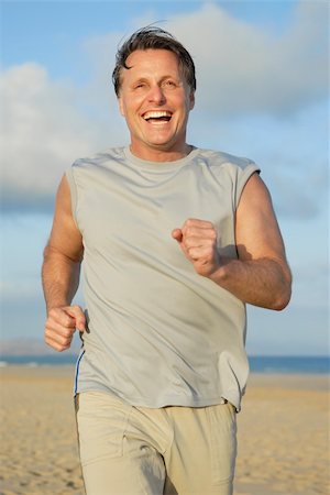 A handsome laughing forties man is having fun as he runs along a beautiful empty beach on the island of fuerteventura in the canary islands. Foto de stock - Super Valor sin royalties y Suscripción, Código: 400-04618489