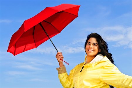 Portrait of beautiful girl wearing yellow raincoat holding red umbrella on windy day Stock Photo - Budget Royalty-Free & Subscription, Code: 400-04619874