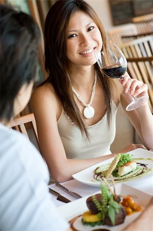 eastwestimaging (artist) - A young woman smiling whilst eating dinner at a restaurant Fotografie stock - Microstock e Abbonamento, Codice: 400-04610146